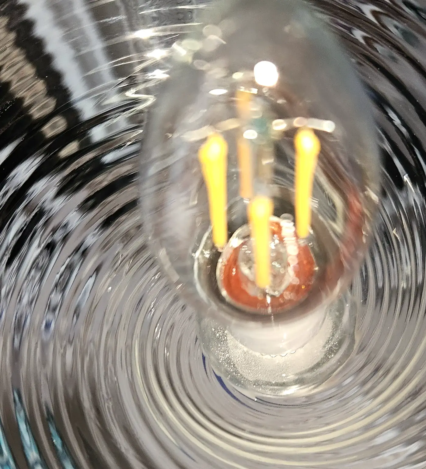 Clear ribbed hand-blown glass shade viewed straight down with a filament bulb at the centre