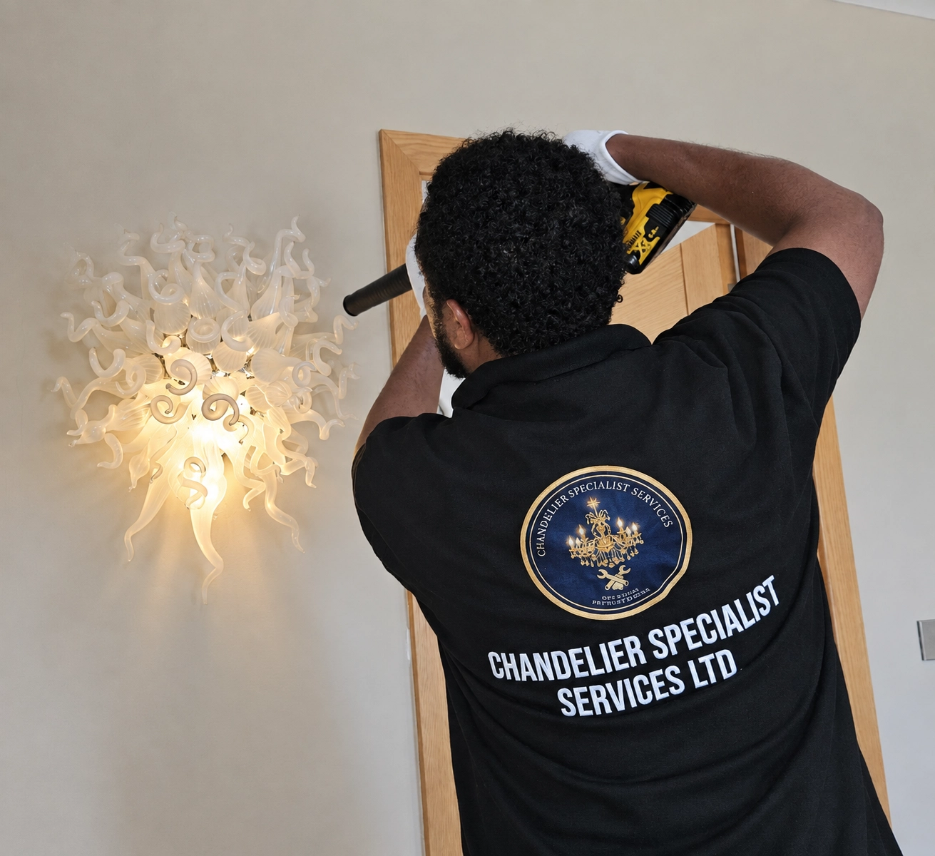 Chandelier specialist beside a wall-mounted white hand-blown glass swirl light