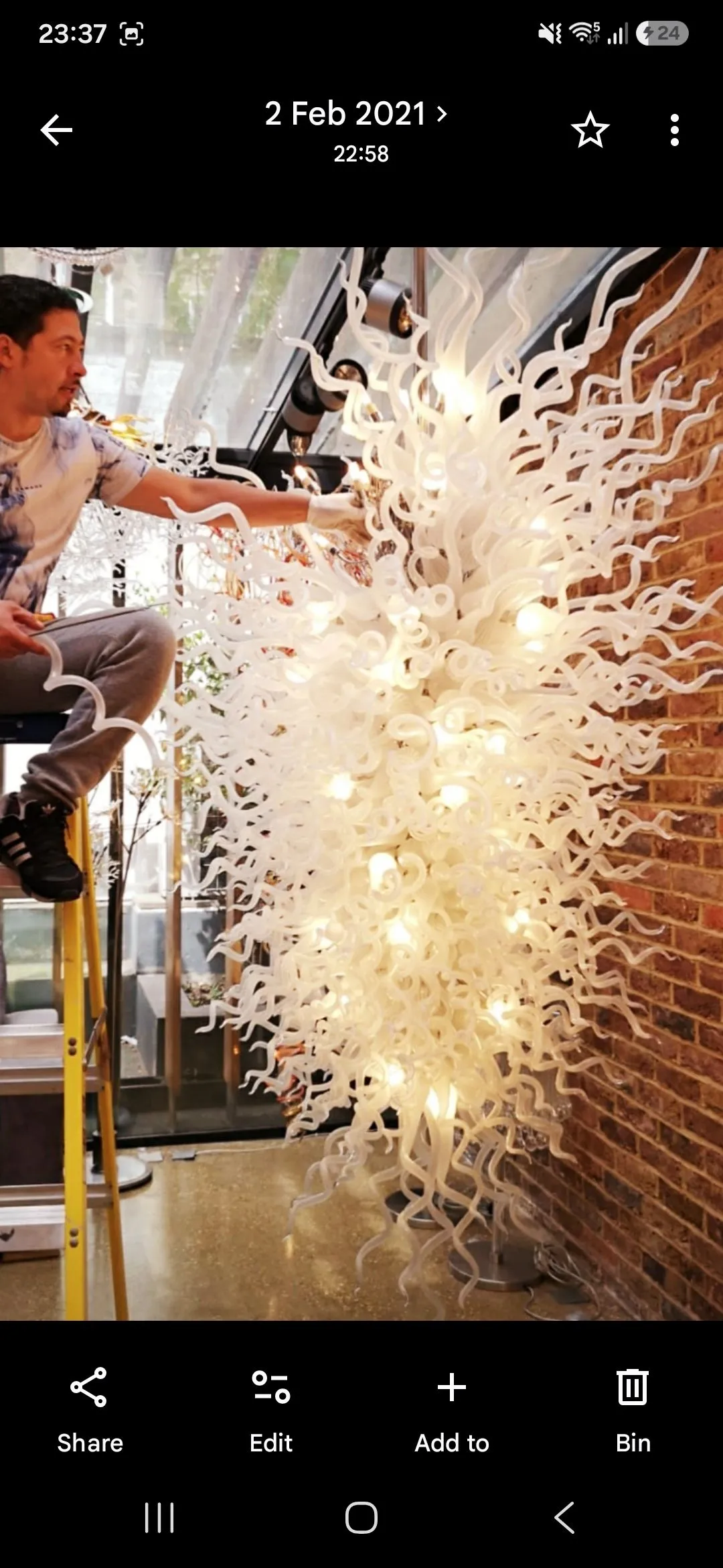 Tall glass chandelier suspended in a stairwell interior
