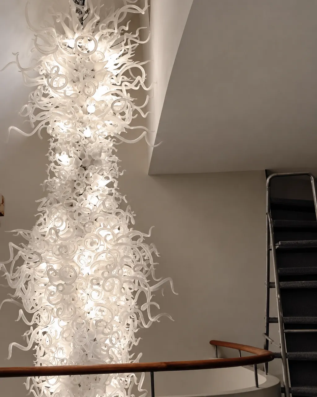Tall white hand-blown glass cascade chandelier in a stairwell